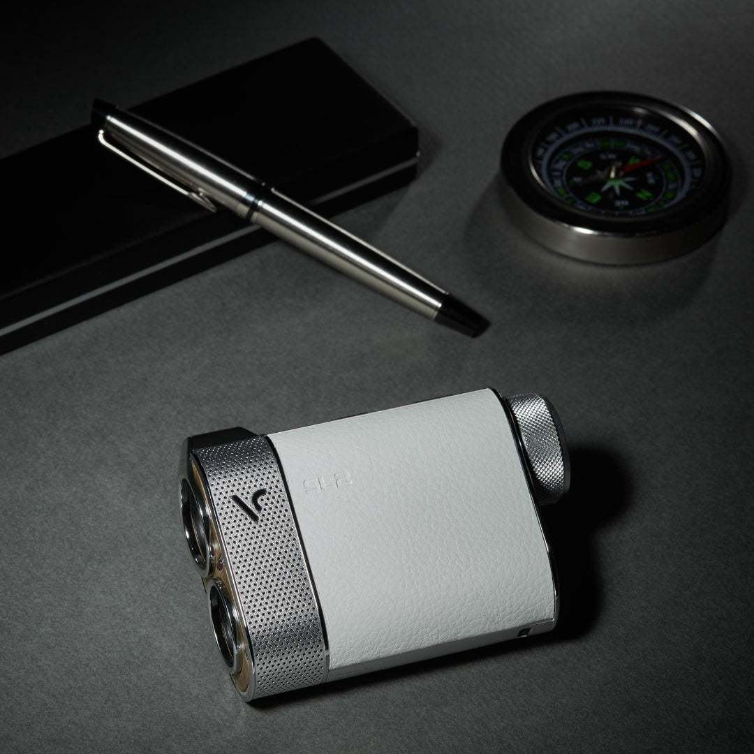 voice caddie sl2 white hybrid gps laser rangefinder next to pen and compass